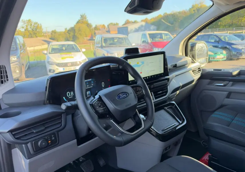 Vue intérieure du poste de conduite du Ford Transit Fourgon 2026, avec tableau de bord numérique et écran tactile central.
