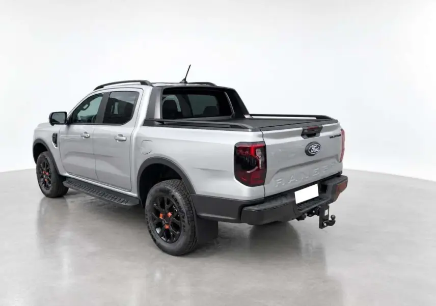 Ford Ranger Wildtrak gris iconic vu en 3/4 arrière droit avec barres de toit et attelage visible.