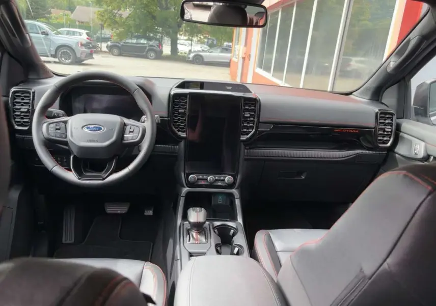Vue intérieure avant du Ford Ranger Wildtrak 2026, tableau de bord noir avec écran vertical et volant multifonctions cuir.