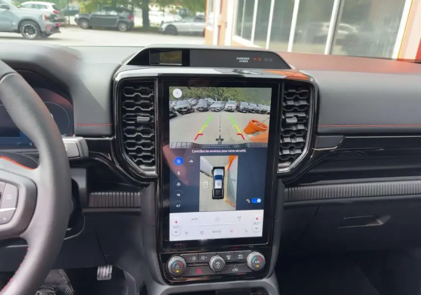 Vue intérieure centrée sur l’écran tactile vertical du Ford Ranger gris, avec tableau de bord noir et volant partiel visible.