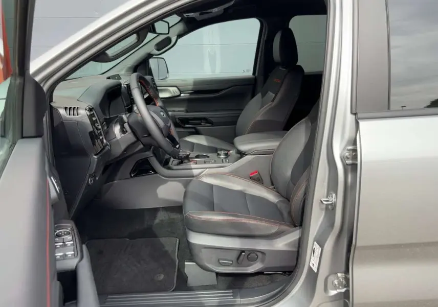 Vue intérieure côté conducteur du Ford Ranger gris iconic 2026, sièges en cuir noir avec surpiqûres orange et tableau de bord moderne.