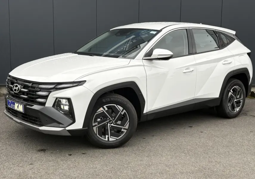Vue 3/4 avant droite du Hyundai Tucson 2026 blanc Serenity avec jantes alliage 17 pouces et calandre noire distinctive.