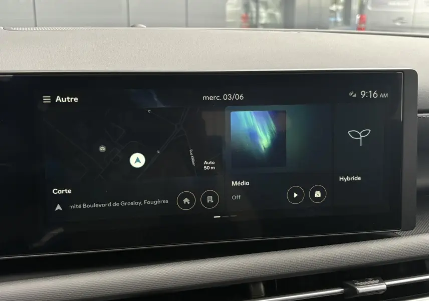 Écran tactile multimédia du Hyundai Tucson 2026 affichant navigation, média et mode hybride, vue intérieure centrale.