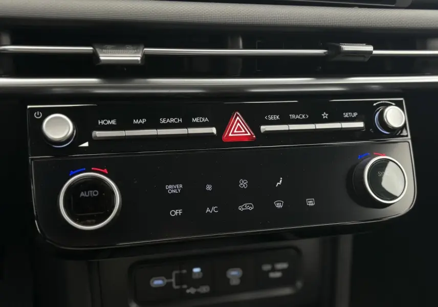 Gros plan sur la console centrale noire du Hyundai Tucson 2026, avec commandes climatisation et multimédia visibles.