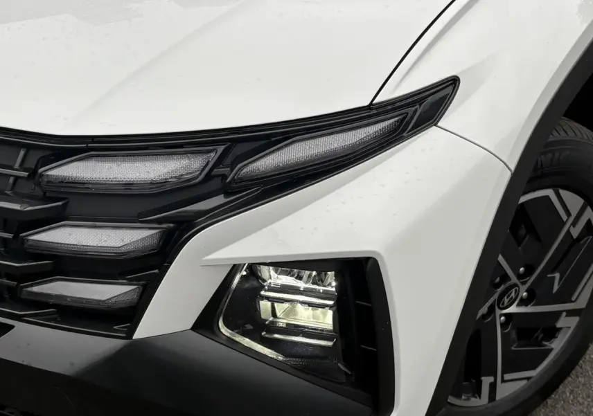Gros plan sur l'avant droit du Hyundai Tucson blanc Serenity, avec ses phares LED et jante alliage 17 pouces.