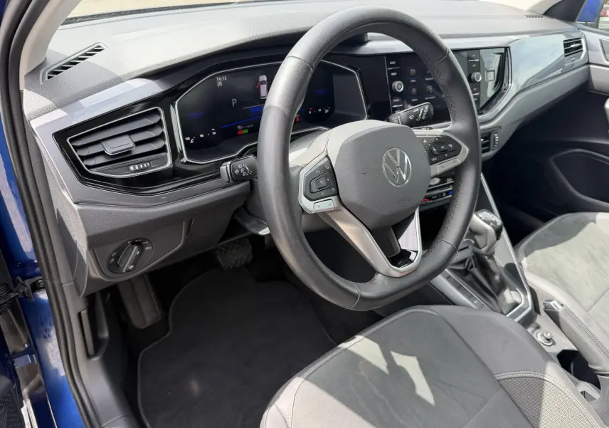 Vue intérieure côté conducteur de la Volkswagen Polo bleue 2025, volant cuir multifonctions et tableau de bord digital.