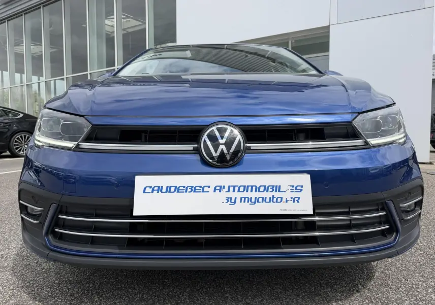 Vue frontale rapprochée d’une Volkswagen Polo bleue 2025 avec calandre noire et logo VW central brillant.
