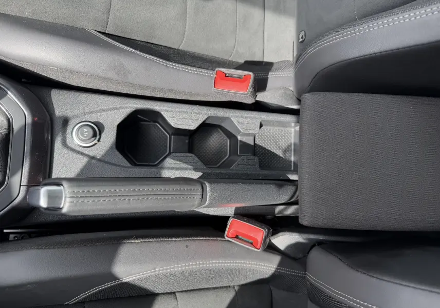 Vue plongeante sur la console centrale noire de la Volkswagen Polo avec frein à main cuir et porte-gobelets.