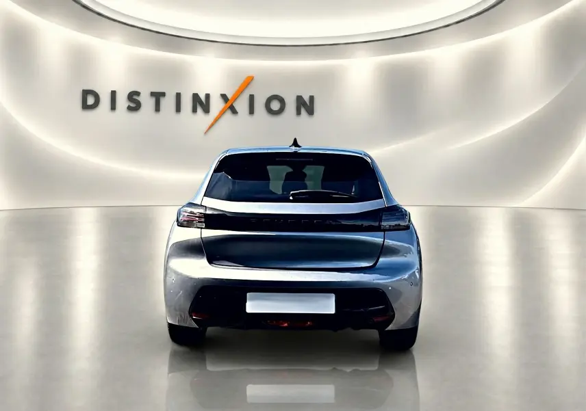 Vue arrière centrée de la Peugeot 208 1.2 100 Allure gris Artense dans un showroom lumineux avec logo Distinxion.