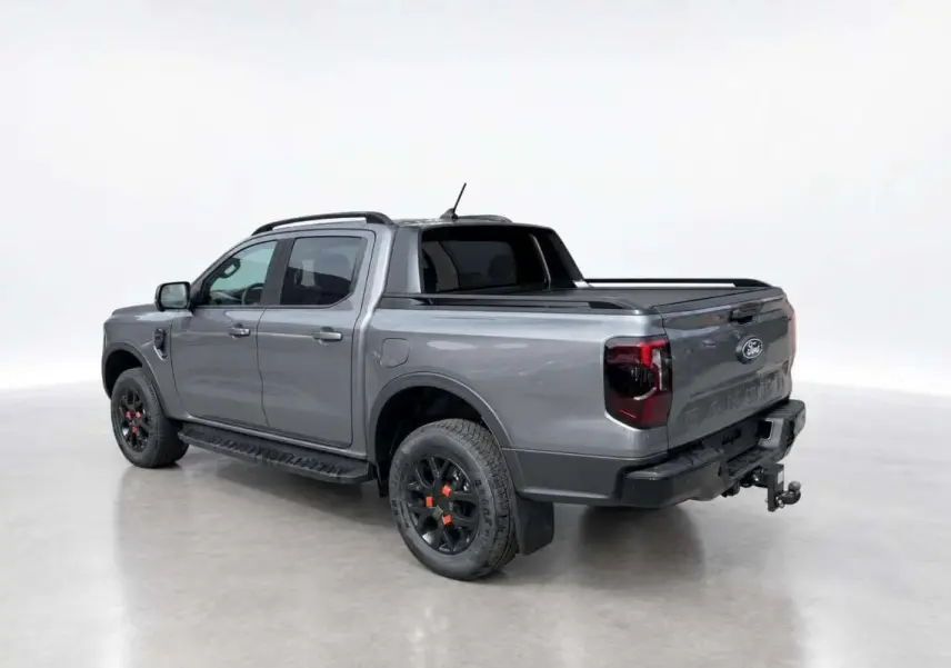 Ford Ranger Wildtrak gris carbone vu en 3/4 arrière droit, avec jantes noires et attelage visible.