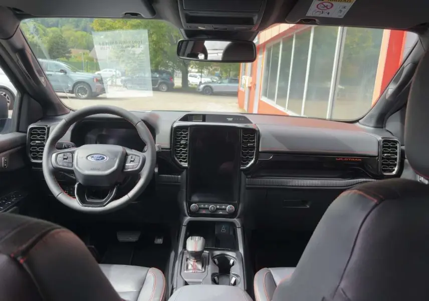 Vue intérieure avant du Ford Ranger Wildtrak 2026 avec tableau de bord noir, écran central vertical et volant cuir multifonctions.