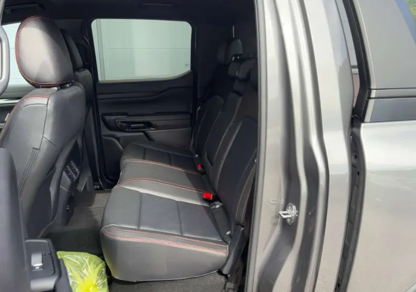 Vue intérieure côté droit sur la banquette arrière en cuir noir avec surpiqûres orange du Ford Ranger gris carbone 2026.