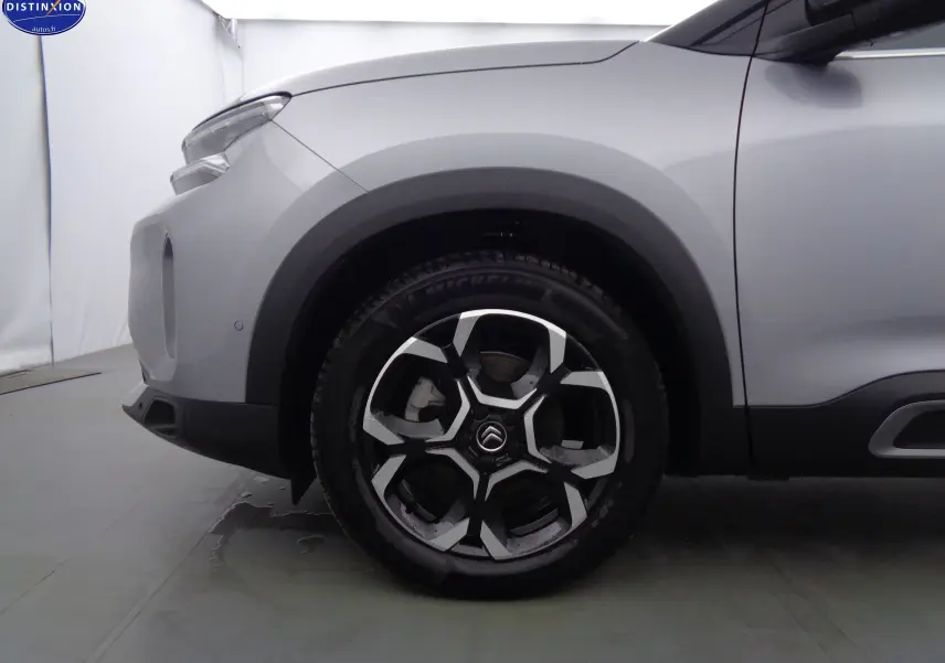 Gros plan sur la roue avant gauche d'un Citroën C5 Aircross gris Artense métal avec jante alliage noire et argent.