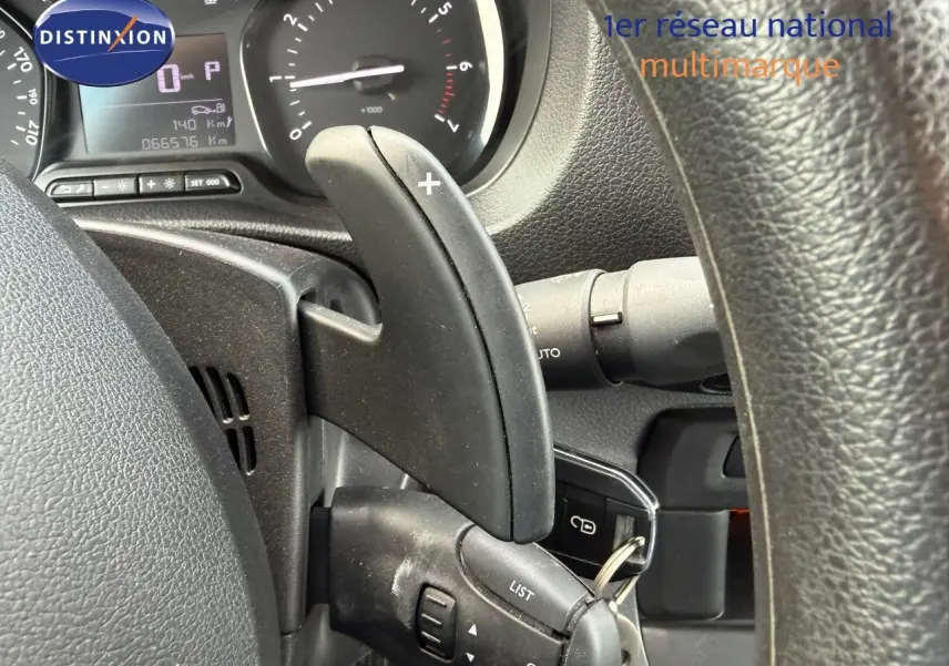 Gros plan sur la commande de boîte automatique au volant d'un Opel Vivaro Fourgon gris Pierre de Lune, tableau de bord visible.