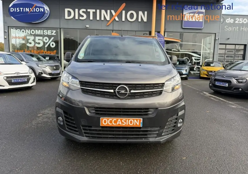 Vue frontale d'un Opel Vivaro Fourgon gris Pierre de Lune métallisé avec plaque "OCCASION" sur fond neutre.