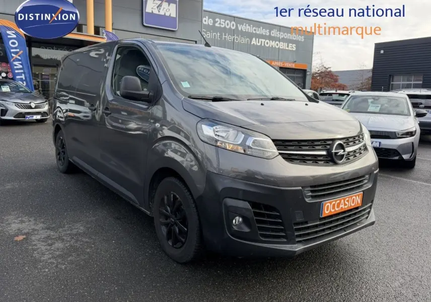 Opel Vivaro Fourgon gris Pierre de Lune métallisé vu en 3/4 avant droit avec calandre noire et jantes foncées.