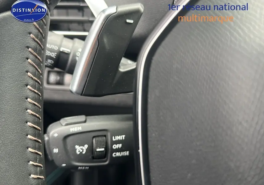 Gros plan sur la commande de régulateur de vitesse au volant cuir noir du Peugeot 5008 bleu 2024.