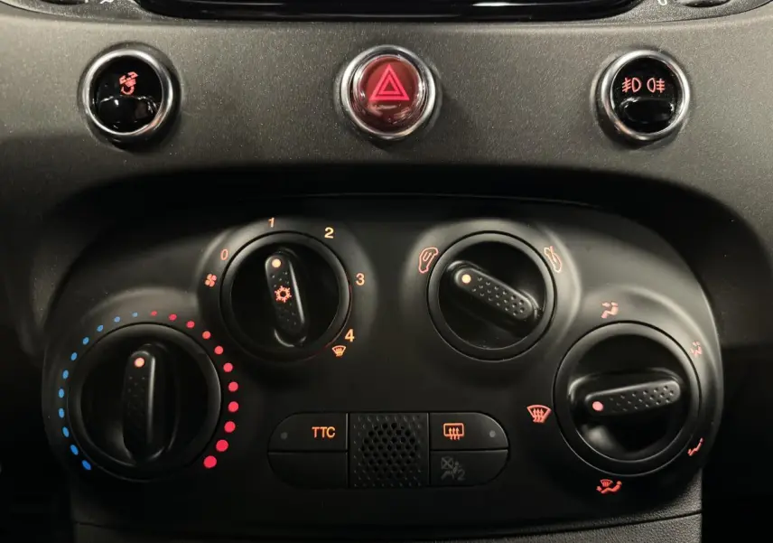 Vue rapprochée du tableau de bord noir de l'Abarth 595 Competizione avec commandes de climatisation et bouton TTC éclairés.
