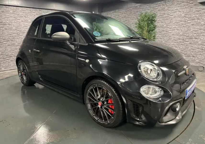 Vue 3/4 avant droite d'une ABARTH 595 Competizione noire avec jantes noires et étriers de frein rouges.