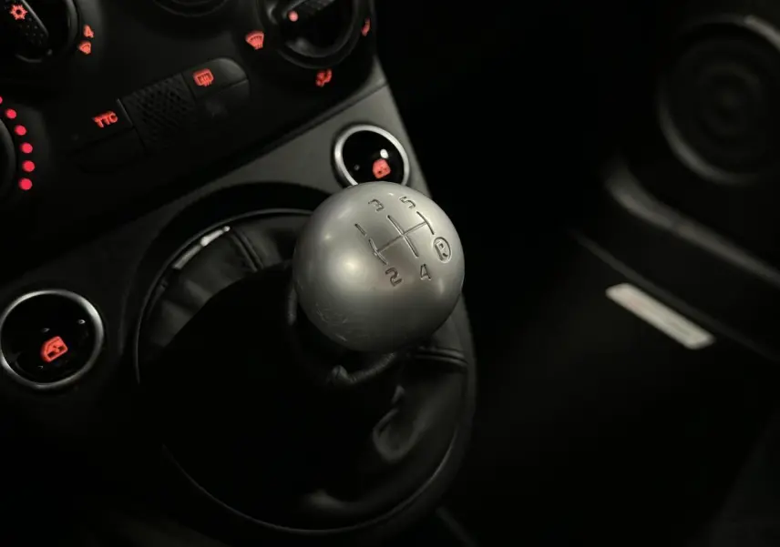 Gros plan sur le pommeau de levier de vitesses aluminium de l'ABARTH 595 Competizione noir, avec commandes éclairées rouges.