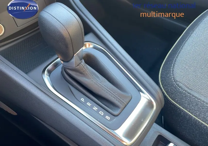 Le levier de vitesses automatique en cuir noir du Renault Captur E-Tech Hybrid 2025, avec console et siège tissu gris.