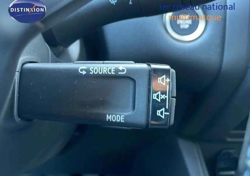 Gros plan sur la commande au volant du Renault Captur blanc nacré, avec bouton source et mode visibles.