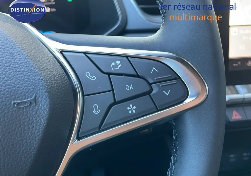 Gros plan sur les commandes au volant du Renault Captur E-Tech blanc nacré, mettant en valeur les boutons multifonctions.