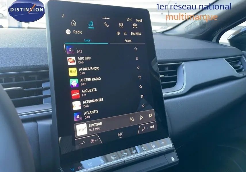 Écran central tactile affichant la liste des radios dans l'habitacle du Renault Captur blanc nacré toit noir, vue de face.
