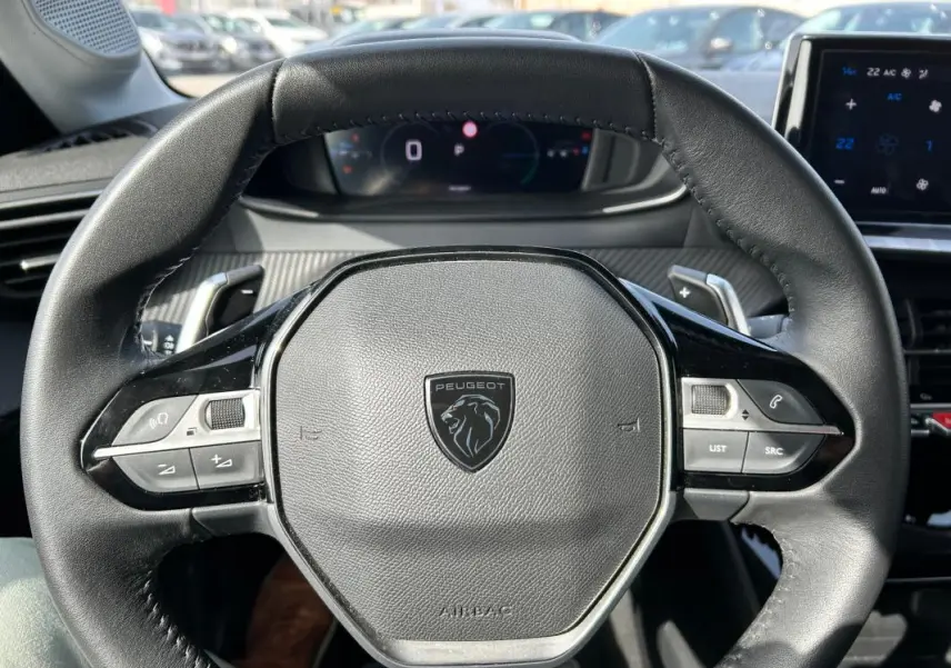 Vue rapprochée du volant cuir noir de la Peugeot 208 Hybrid 110 e-DCS6 Allure 2024 avec commandes intégrées.