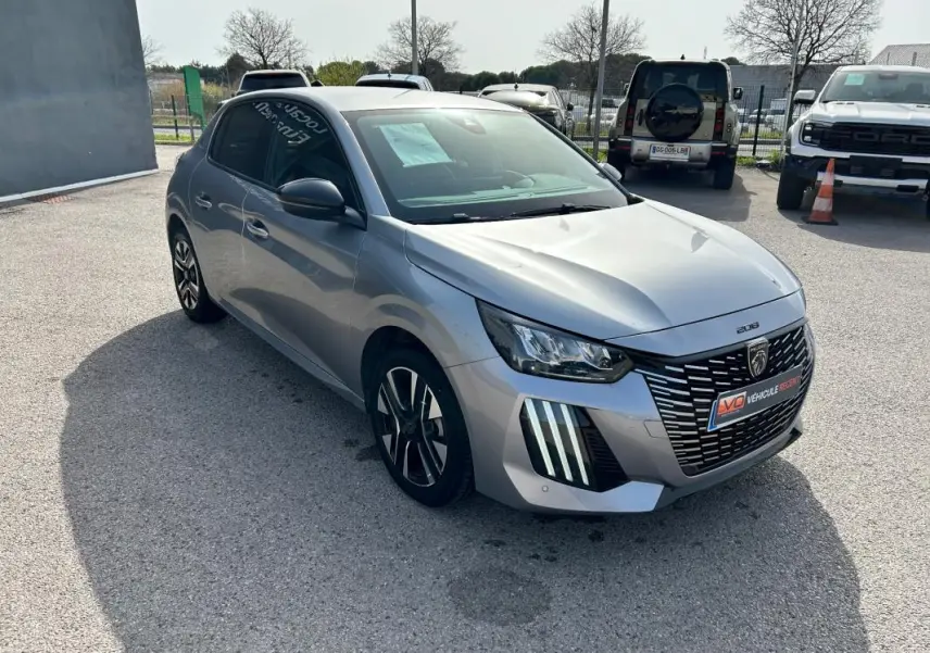 Peugeot 208 Hybrid 110 gris vue 3/4 avant droit, avec calandre distinctive et feux LED verticaux marquants.