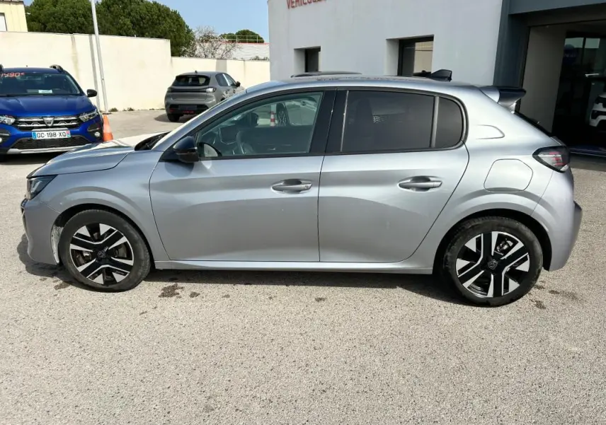 Vue de profil côté gauche d'une Peugeot 208 Hybrid 110 gris métallisé avec jantes noires et argentées, modèle 2024.