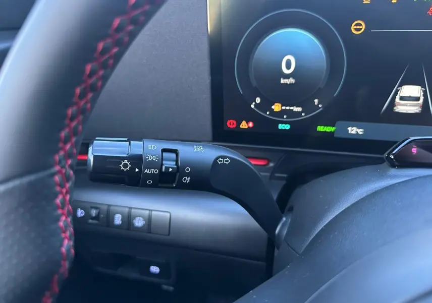 Gros plan sur le volant noir avec surpiqûres rouges et le combiné d'instruments numérique du Hyundai Kona 2026.