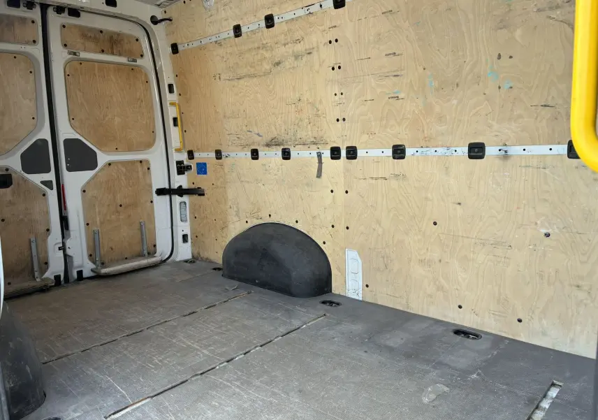 Vue intérieure arrière du fourgon Volkswagen Crafter blanc avec parois et plancher en bois, porte latérale droite ouverte.