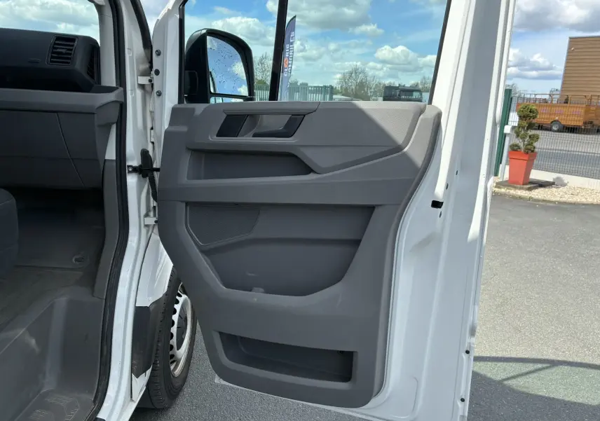Vue rapprochée de la porte avant droite ouverte du Volkswagen Crafter blanc, montrant le panneau intérieur gris.