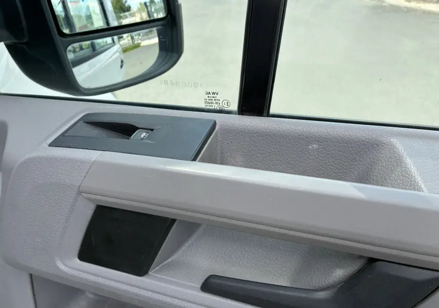 Détail de la porte intérieure côté conducteur du Volkswagen Crafter blanc, avec commande de vitre électrique visible.