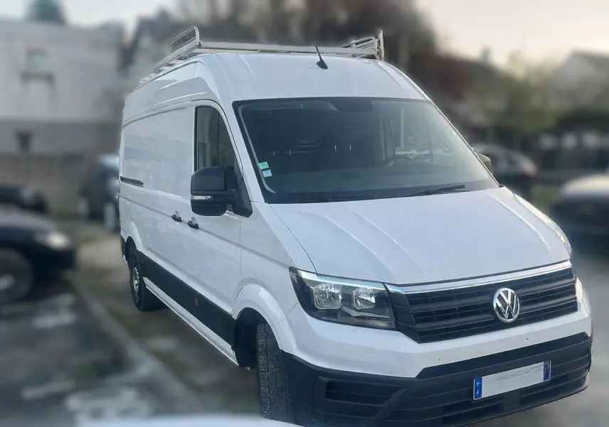 Vue frontale d'un Volkswagen Crafter blanc avec calandre noire et plaque Distinxion visible.