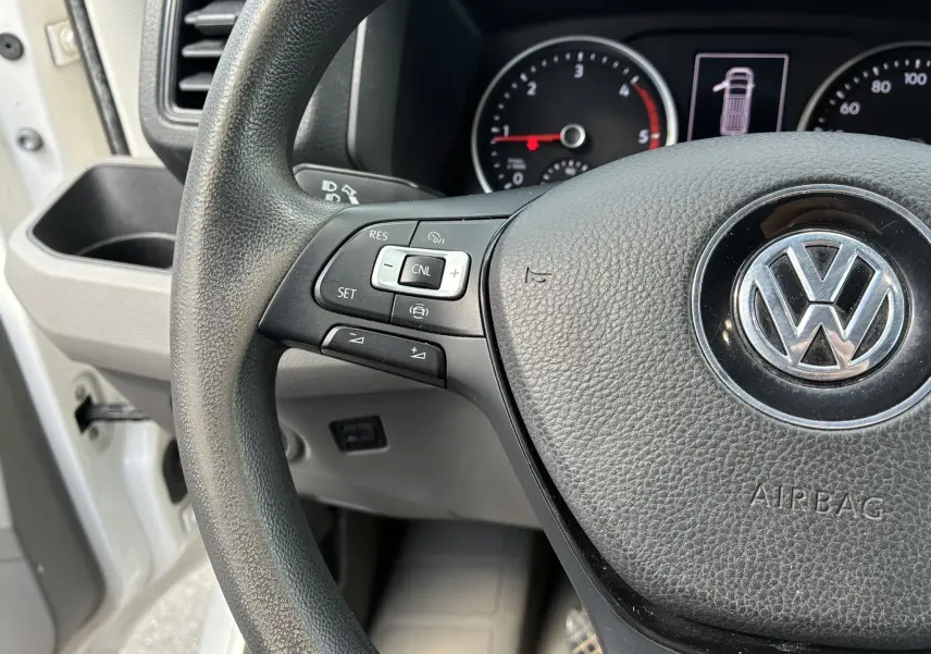 Gros plan sur le volant multifonctions noir et le tableau de bord du Volkswagen Crafter blanc, côté conducteur.