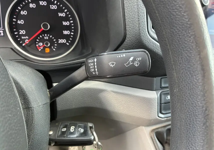 Gros plan sur la manette d’essuie-glace noire à droite du volant dans le tableau de bord du Volkswagen Crafter blanc.