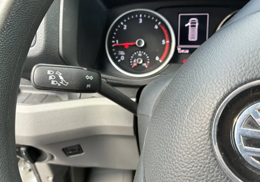Gros plan sur le volant noir et le tableau de bord du Volkswagen Crafter blanc, avec compte-tours et indicateur d'ouverture de porte.