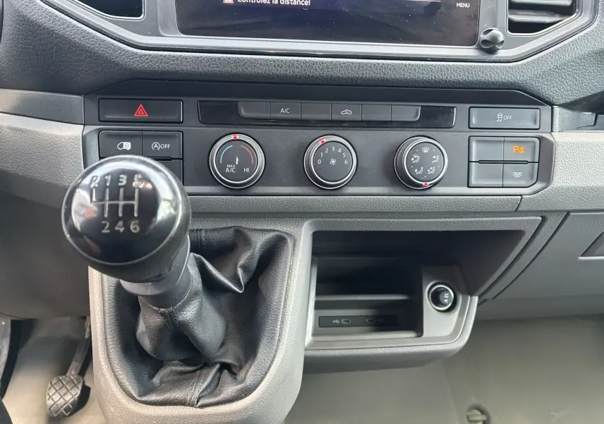 Gros plan intérieur sur la console centrale noire du Volkswagen Crafter avec levier de vitesse manuel et commandes de climatisation.