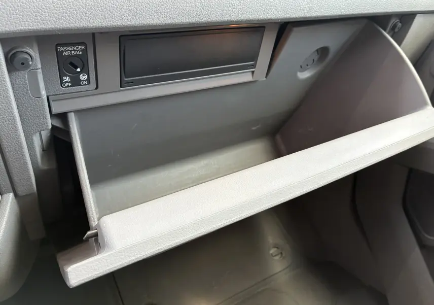 Vue rapprochée de la boîte à gants ouverte grise dans l'habitacle du Volkswagen Crafter Fourgon blanc 2020.