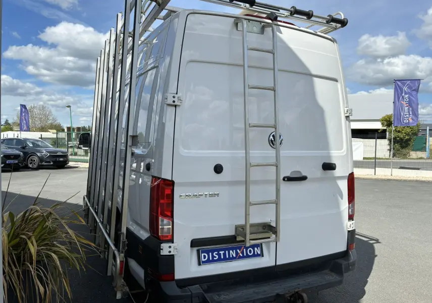 Vue arrière d’un Volkswagen Crafter blanc avec échelle métallique et porte-outils sur le côté droit.