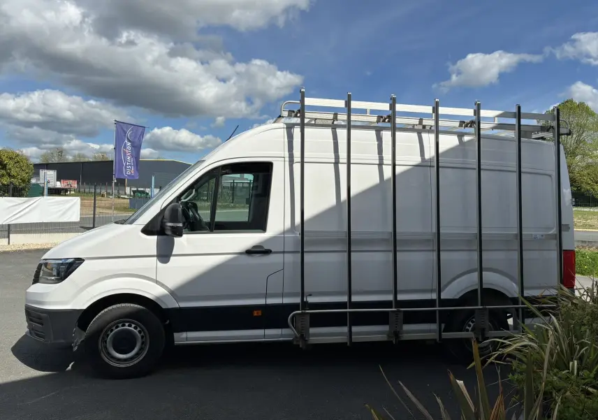 Vue de profil côté gauche d’un Volkswagen Crafter fourgon blanc équipé d’un porte-verre métallique sur le toit.