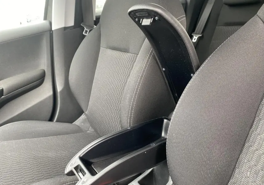 Vue intérieure rapprochée du siège avant droit d'une Peugeot 208 gris, avec accoudoir central ouvert et tissu texturé.