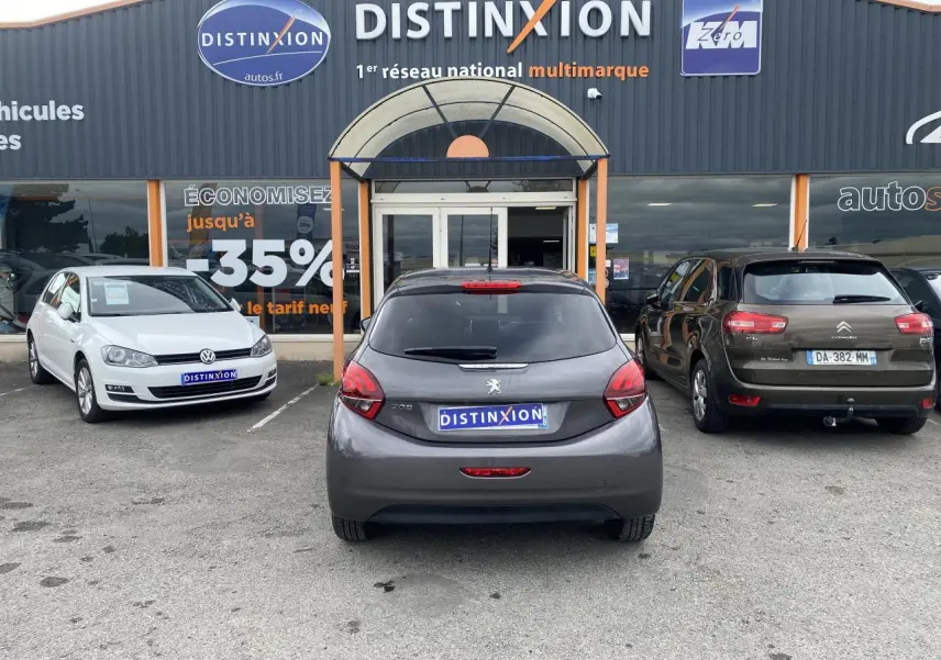 Vue arrière d'une Peugeot 208 gris métallisé garée devant un concessionnaire multimarque Distinxion.