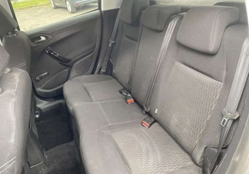 Vue intérieure de la banquette arrière en tissu gris foncé de la Peugeot 208 1.2i 2018, avec ceintures de sécurité visibles.