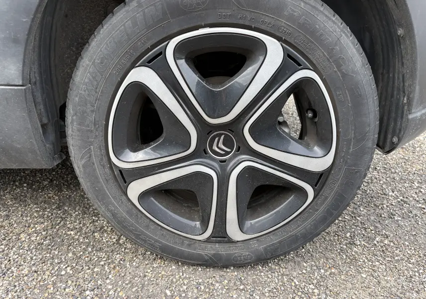 Gros plan sur la roue avant gauche d'une Citroën C3 beige 2019, avec jante noire et argent au design moderne.