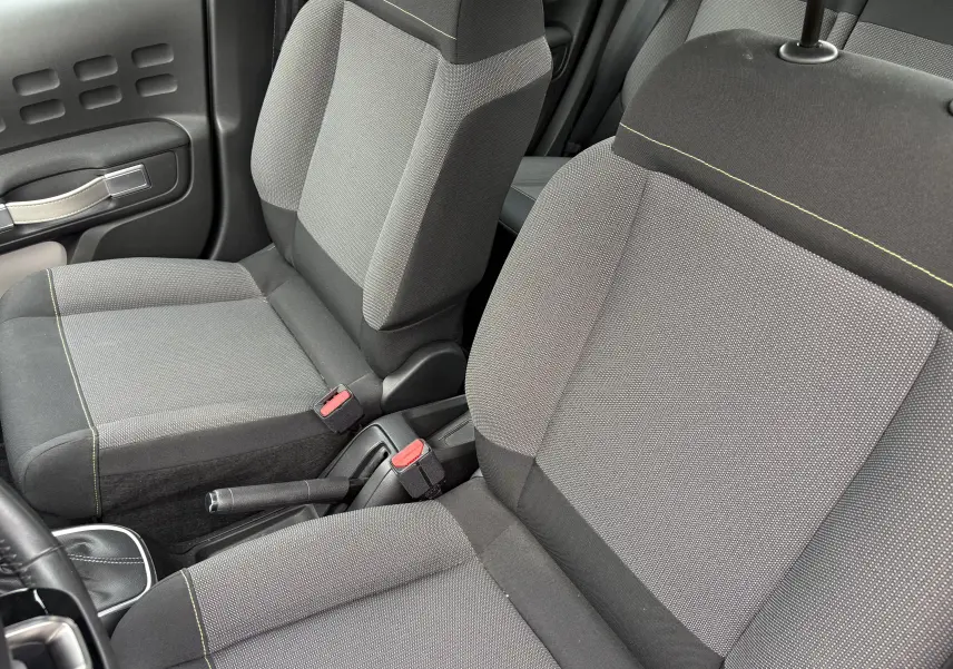 Vue rapprochée des sièges avant gris avec surpiqûres jaunes d'une Citroën C3 beige de 2019, version Shine.