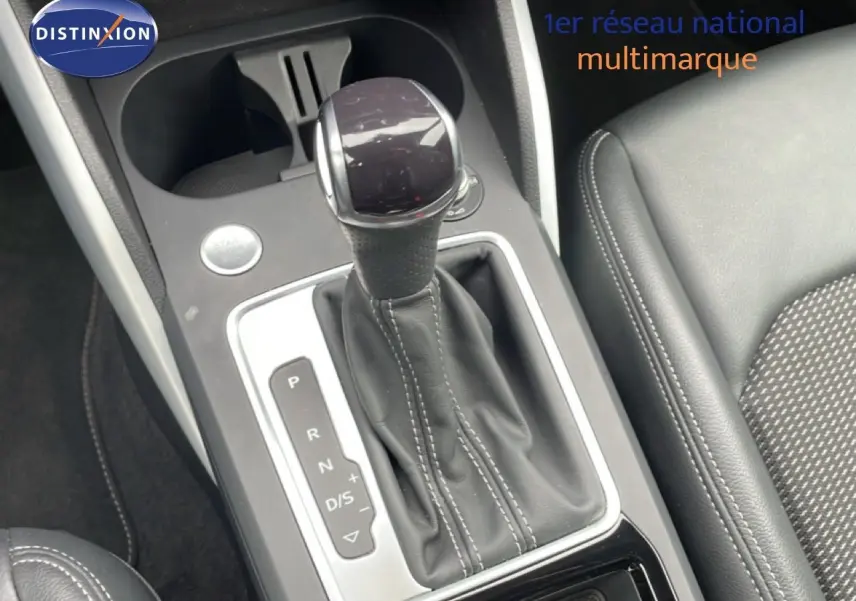Gros plan sur la commande de boîte automatique noire avec surpiqûres blanches dans l'Audi Q2 35 2.0 TDI S-Line.