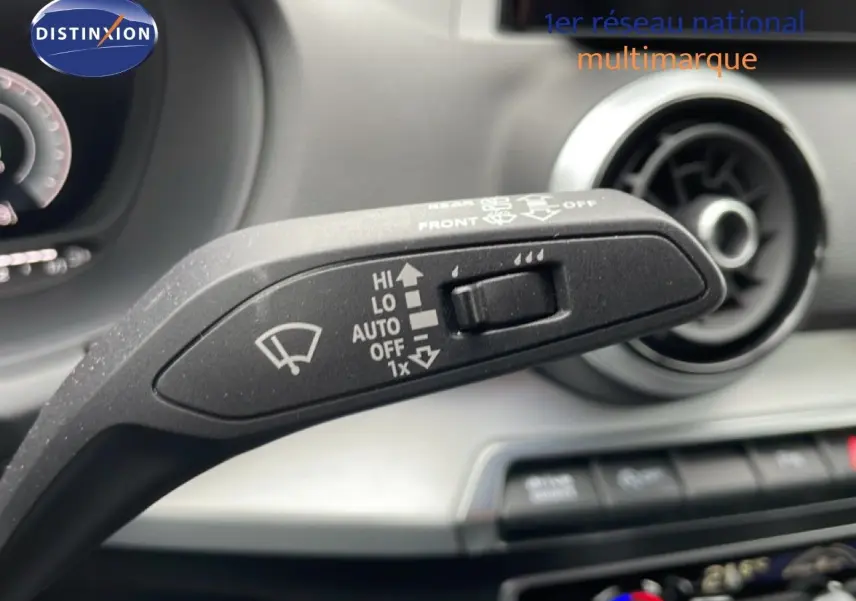 Gros plan sur la commande des essuie-glaces de l'Audi Q2 2025, intérieur noir avec aérateur circulaire en arrière-plan.